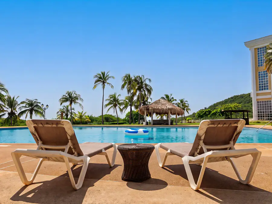 Piscina con palmeras y camastros